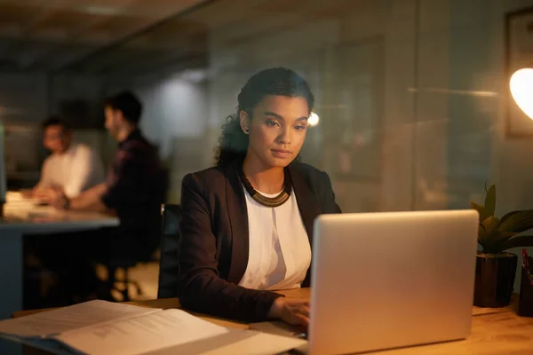 Brûler l'huile de minuit. Prise de vue d'une jeune femme d'affaires utilisant son ordinateur portable pendant qu'elle faisait des heures supplémentaires au bureau. — Photo