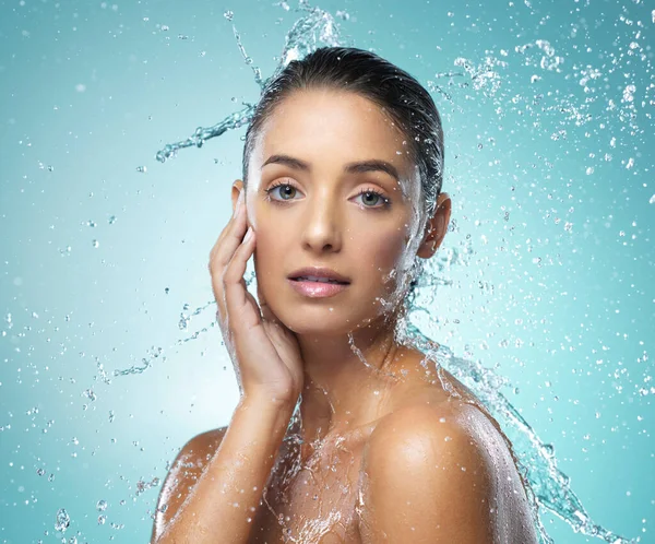 Ihre Haut fühlt sich weich an. Aufnahme einer jungen Frau beim Duschen vor blauem Hintergrund. — Stockfoto