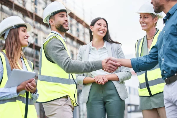 Wanneer we ernaar streven om beter te worden dan we zijn. Schot van een team van bouwers die elkaar de hand schudden op een bouwplaats buiten. — Stockfoto