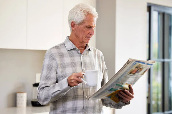 Dame un periódico y un poco de té y estoy feliz. Fotografía de un hombre maduro leyendo un periódico. —  Fotos de Stock