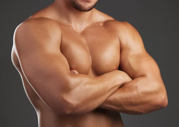 Confidently macho. Closeup shot of an unrecognizable and athletic young mans chest while he poses arms folded in studio against a dark background. — Stock Photo, Image
