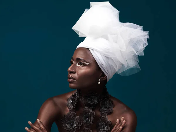 Still høye krav til deg selv. Studioopptak av en attraktiv ung kvinne i tradisjonelt afrikansk antrekk mot en blå bakgrunn. – stockfoto