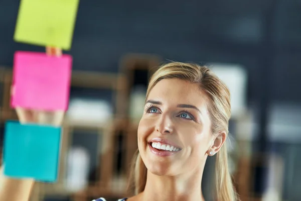 Improving business with a well laid out plan. Shot of a young woman having a brainstorming session with sticky notes at work. — Stock Photo, Image