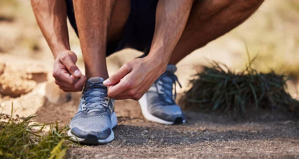 Its time to work for that muscle. Cropped shot of an unrecognizable man crouching down to tie his shoelaces before going on an outdoor run.