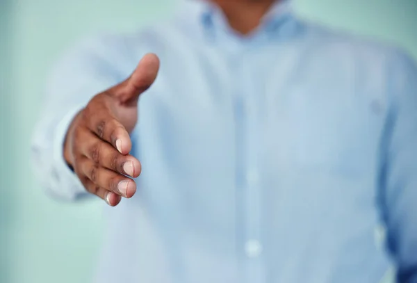 Graag gedaan. Gehakt schot van een onherkenbare zakenman staan met zijn hand uitgestrekt voor een handdruk tegen een blauwe achtergrond. — Stockfoto