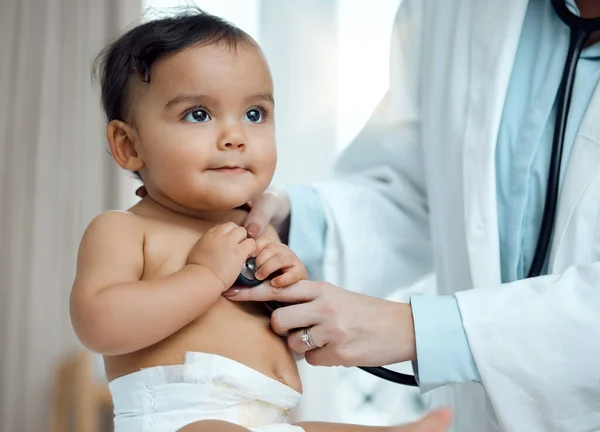 Vad är det du hör, doktorn? Närbild bild bild av en barnläkare med hjälp av ett stetoskop under en babys kontroll på en klinik. — Stockfoto