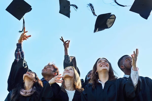 Lo logramos. Foto de un grupo de estudiantes lanzando sus sombreros al aire en el día de la graduación. —  Fotos de Stock
