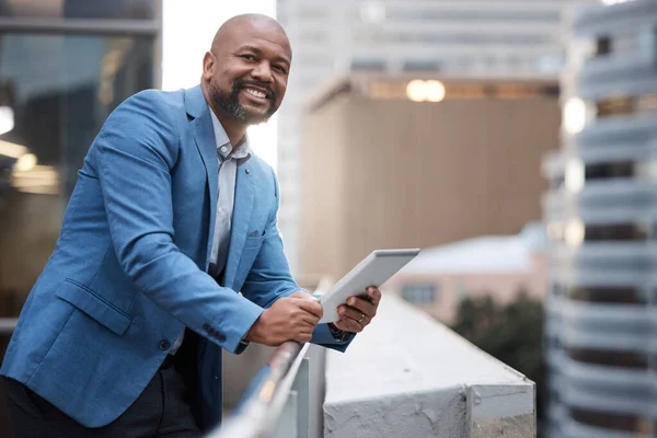 Так я остаюсь впереди. Портрет взрослого бизнесмена с цифровой табличкой, стоящего на балконе за пределами офиса. — стоковое фото