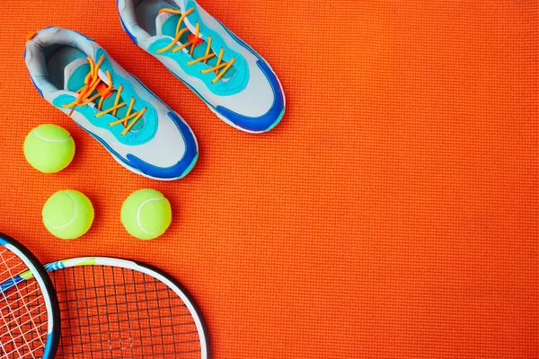 Uno necesita muy buenos zapatos para esto. Tiro de alto ángulo de elementos esenciales de tenis colocados sobre un fondo naranja dentro de un estudio. —  Fotos de Stock
