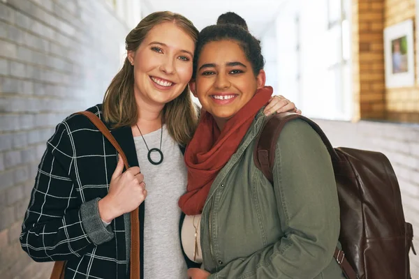 El campus es mejor con ella a mi lado. Retrato de dos jóvenes y atractivas estudiantes universitarias de pie en un pasillo del campus. — Foto de Stock