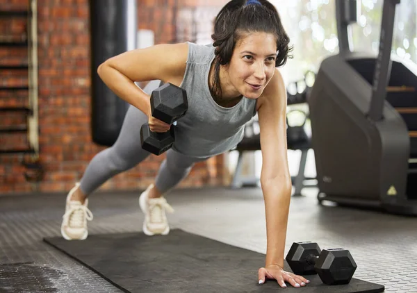 Al levantar pesas, se construye el músculo magro. Foto de una joven deportista haciendo ejercicio con pesas en un gimnasio. —  Fotos de Stock