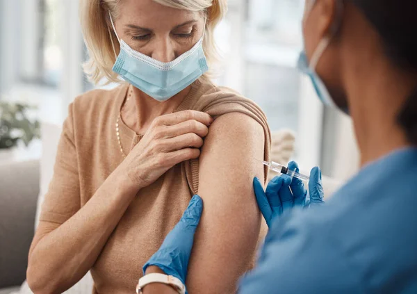 Un seul connard te protège. Prise de vue d'un médecin donnant une injection à une femme âgée à la maison. — Photo