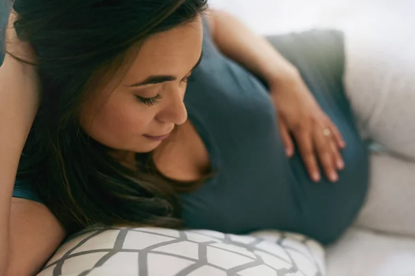 Faire des liens entre maman et bébé. Prise de vue d'une jeune femme enceinte se relaxant à la maison. — Photo