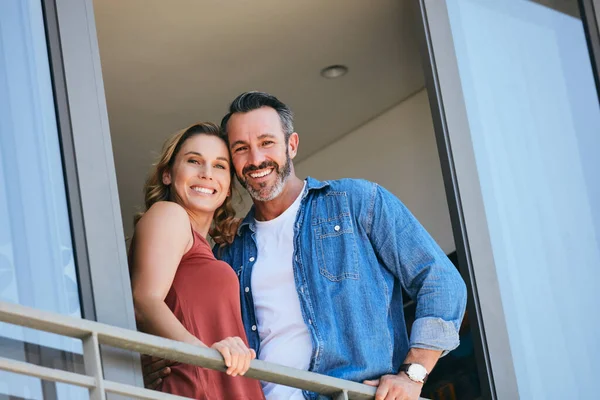 Aquí es donde llamamos hogar. Retrato de una feliz pareja de pie en el balcón de su casa. — Foto de Stock