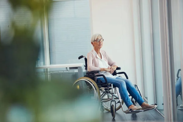Kto by pomyślał, że to się tak skończy. Pełne ujęcie starszej kobiety wyglądającej troskliwie, siedzącej na wózku inwalidzkim w domu spokojnej starości. — Zdjęcie stockowe