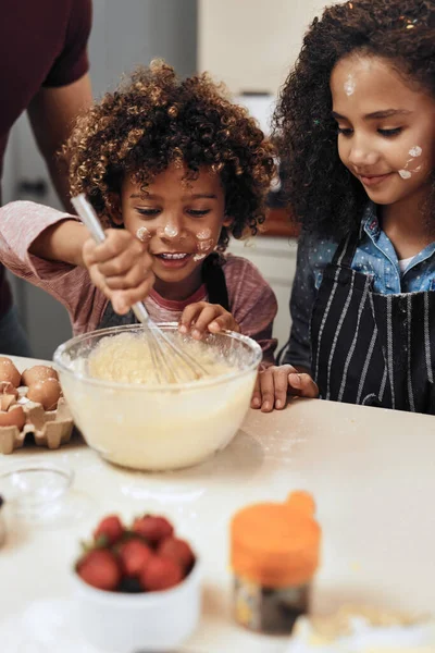 Plezier hebben tijdens het leren van moeders speciaal recept. Gesneden schot van een jonge jongen en meisje bakken in de keuken thuis. — Stockfoto