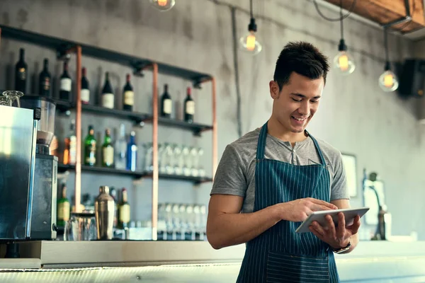 Gestionar su negocio en línea. Recorte de un joven trabajando en una tableta en su cafetería. — Foto de Stock