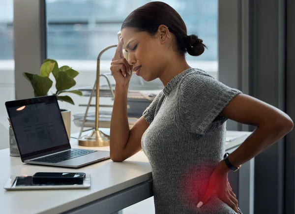 I really need to lie down. Shot of a young businesswoman experiencing a headache and back pain in her office. — Stock Photo, Image