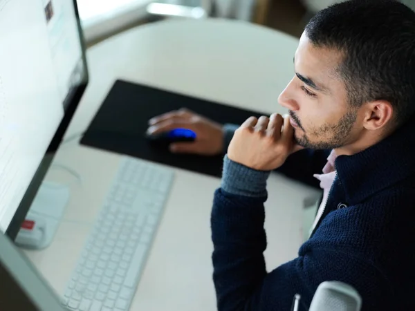 彼の百パーセントの仕事を与えること。焦点を当てた若い男のショット机の上に座ってデュアルモニターでコンピュータ上で作業. — ストック写真