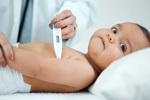 Låt oss börja med att ta din temperatur. Skjuten av en barnläkare som tar en barntemperatur med en termometer på en klinik. — Stockfoto