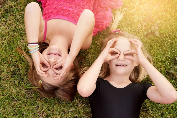 아이가 된다는 것은 정말 재미있는 일입니다. 두 어린 소녀 가 바깥 풀밭에 누워 재미있게 노는 모습. — 스톡 사진