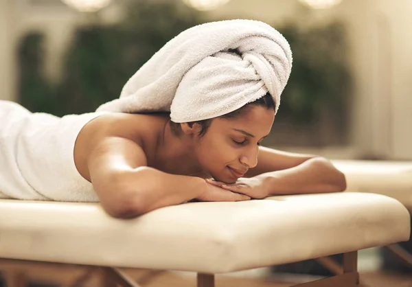 Reduzca la velocidad y desestrese. Fotografía de una joven sonriendo tumbada en una cama de masaje en un spa. —  Fotos de Stock