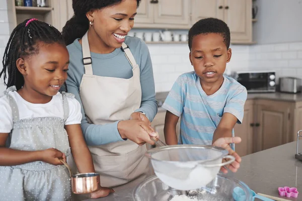 Familieleden kunnen je beste vrienden zijn. Shot van een moeder bakken met haar kinderen thuis. — Stockfoto
