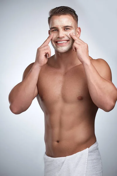 Trying to find my place. Studio portrait of an attractive young man applying a beauty treatment to his face against a grey background. — Stock Photo, Image