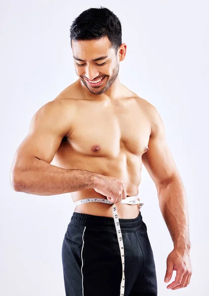 Um meine Ziele bei der Gewichtsabnahme zu erreichen. Aufnahme eines männlichen Athleten, der seine Taille vor weißem Studiohintergrund misst. — Stockfoto
