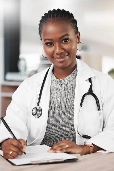 Vieni a trovarmi per un certificato di buona salute. Girato di un giovane medico prendere appunti alla sua scrivania. — Foto Stock