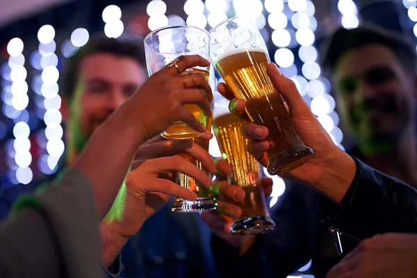 Hay buenos momentos con los mejores amigos. Foto de un grupo de jóvenes amigos brindando con vasos de cerveza en un club nocturno. — Foto de Stock