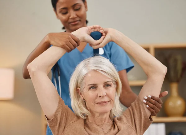 Een gezond hart houdt je sterk. Schot van een oudere vrouw met halters tijdens een examen met haar arts thuis. — Stockfoto