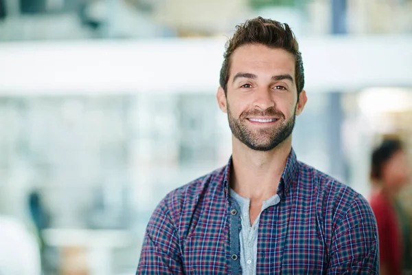 Hij glimlacht zich een weg naar succes. Portret van een gelukkige jonge zakenman in zijn kantoor. — Stockfoto