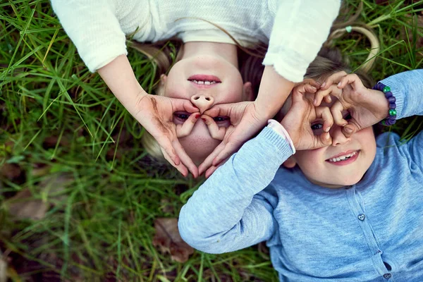 젊다는 것은 쉬지 않고 즐기는 것입니다. 바깥 풀밭에 누워 있는 두 어린 자매의 모습. — 스톡 사진