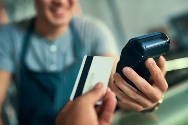 Põe no meu cartão. Tiro recortado de um barista irreconhecível a receber um pagamento com cartão de crédito. — Fotografia de Stock