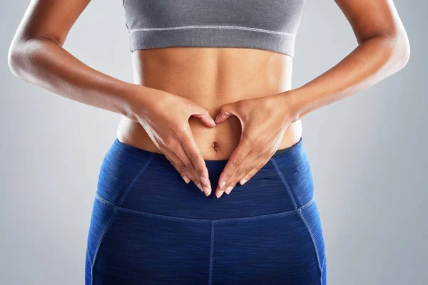 Ama tu cuerpo y te amará de nuevo. Estudio recortado toma de una joven irreconocible haciendo una forma de corazón en su estómago. — Foto de Stock