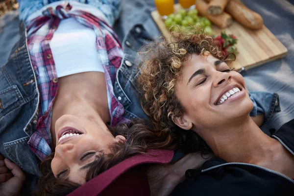 Tu me fais rire sans arrêt. Plan de deux jeunes femmes allongées sur une couverture de pique-nique. — Photo