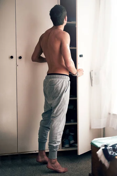 Решения, решения. Фотография молодого человека, ищущего одежду в шкафу своей спальни. — стоковое фото