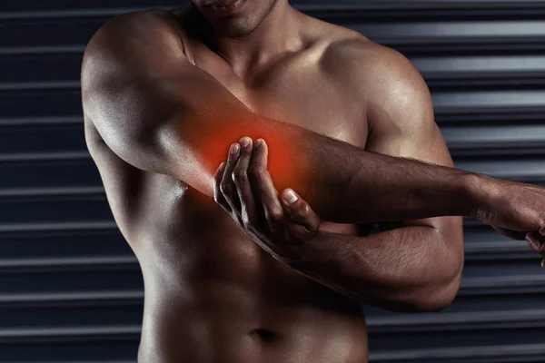 Strek het uit. Schot van een onherkenbare jongeman met zijn elleboog in pijn tijdens een training. — Stockfoto