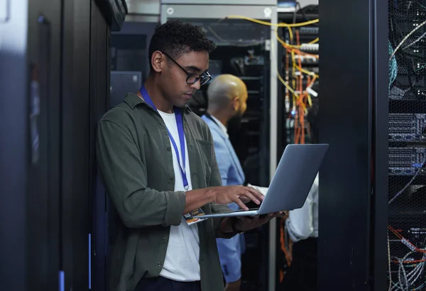 IT-werkzaamheden aan de gang. Gesneden opname van twee mannelijke IT-ondersteuningsagenten die samenwerken in een donkere netwerkserverruimte. — Stockfoto