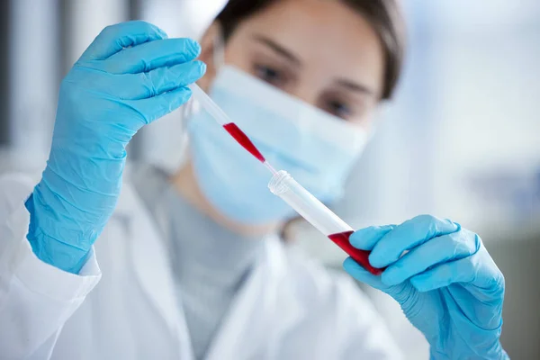 Meerdere tests doen om de resultaten te bevestigen. Close-up shot van een jonge vrouw met behulp van een druppelaar en reageerbuis tijdens het werken met monsters in een lab. — Stockfoto