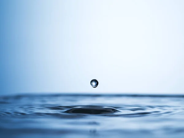 One drop can cause a ripple. Abstract studio shot of a water droplet falling into a puddle of water. — Stock Photo, Image