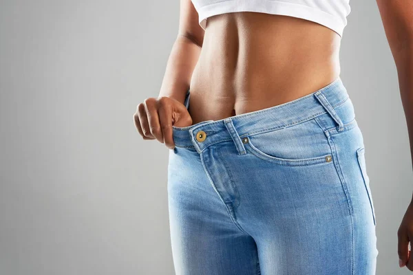 Te mereces la cintura perfecta. Recortado estudio de toma de una joven irreconocible en jeans sobre un fondo gris. — Foto de Stock