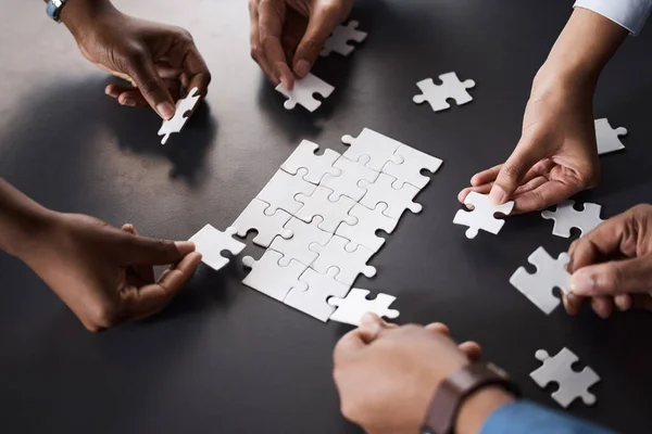 Risolvere i problemi come dovrebbe fare una squadra dedicata. Primo piano di un gruppo di imprenditori irriconoscibili che uniscono pezzi di puzzle in un ufficio. — Foto Stock