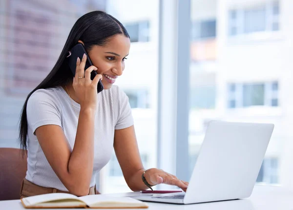 Visst, jag tittar på det just nu. Beskuren bild av en attraktiv ung affärskvinna som ringer ett samtal medan hon arbetar på sin bärbara dator på kontoret. — Stockfoto