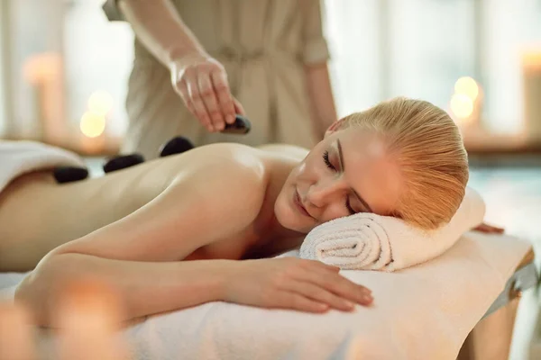 Het is waar de tijd stilstaat. Gesneden schot van een jonge vrouw genieten van een hete steen massage in een spa. — Stockfoto