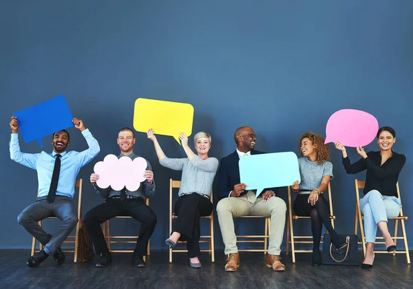 Se siente bien poder decir lo que piensas. Fotografía de un grupo de personas sosteniendo burbujas del habla sobre un fondo azul. — Foto de Stock