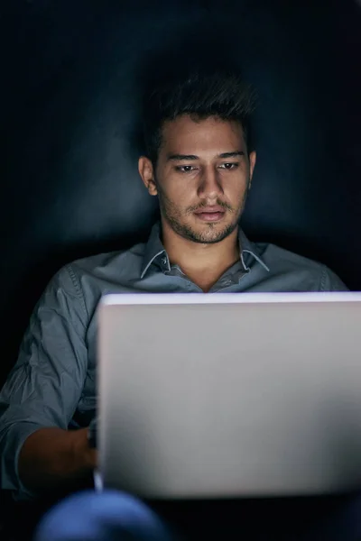 暗闇の中で働いてる。夜にノートパソコンで働いている若い男のショット. — ストック写真
