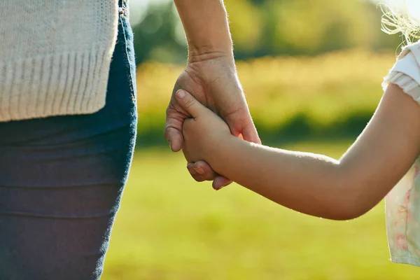 Hou ze dichtbij, bescherm ze. Gehakt schot van een klein meisje met een onherkenbare vrouwenhand in het park. — Stockfoto