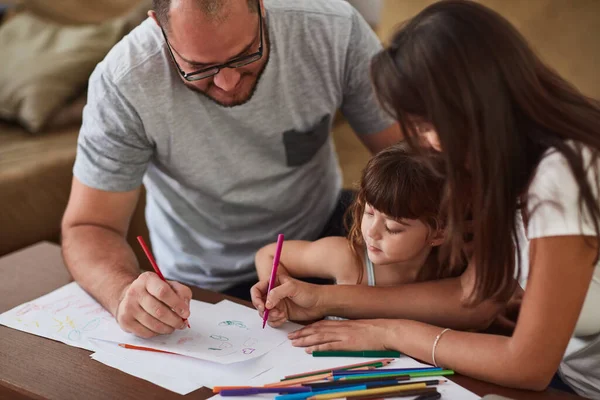 Incoraggiano il gioco creativo nella loro casa. Girato di una madre e un padre che disegnano insieme con la loro giovane figlia a casa. — Foto Stock